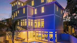 Une maison à plusieurs étages avec une piscine et un espace extérieur aménagé pour se détendre.