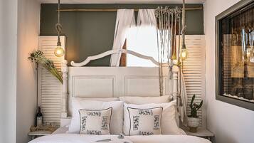 Un dormitorio con cama, mesitas de noche, una ventana con cortinas y una lámpara colgante.