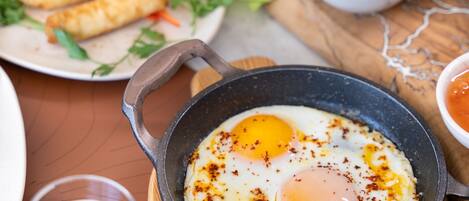 A breakfast setting with a skillet of eggs, toast, and various side dishes.