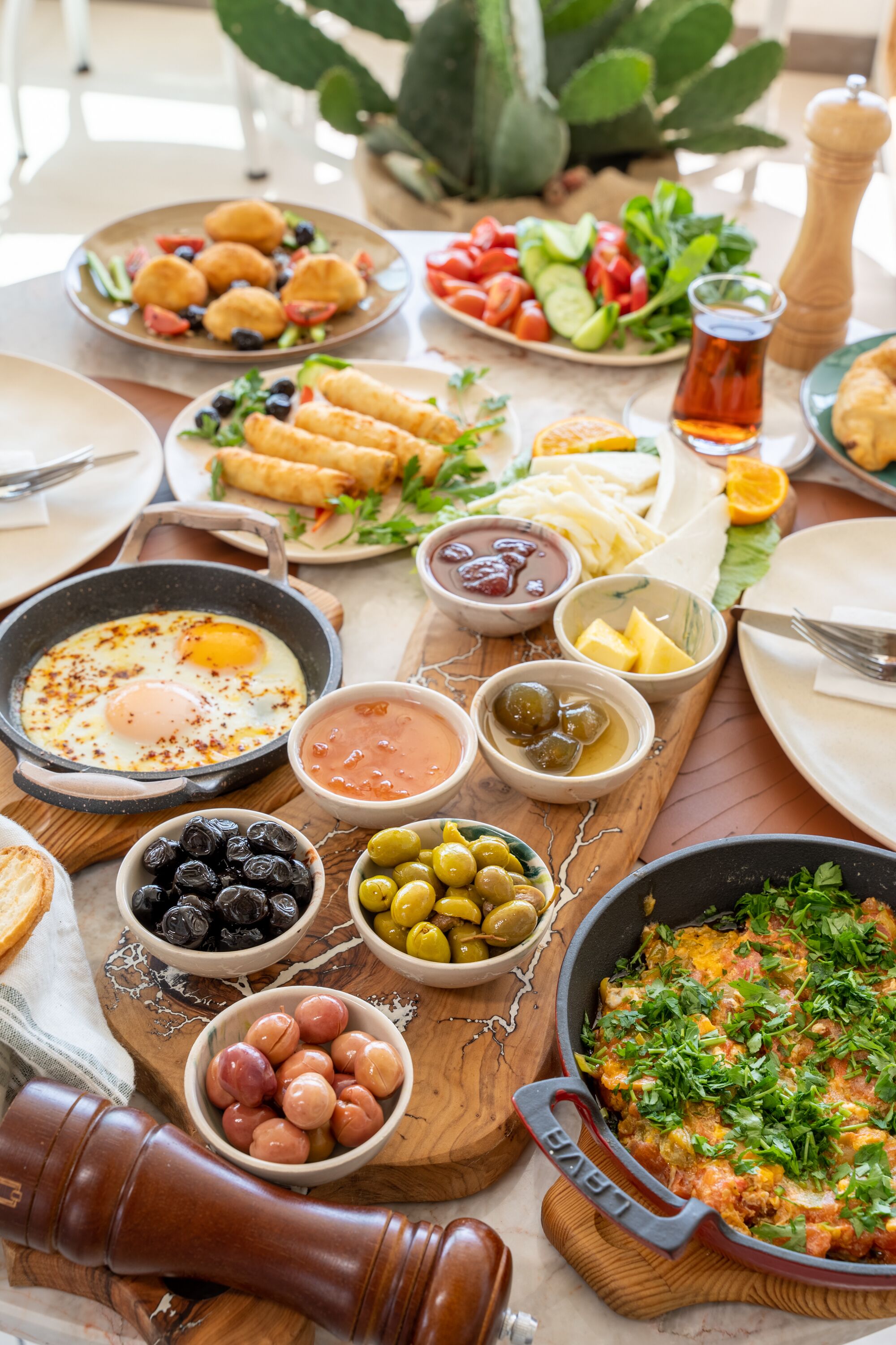 Una mesa con varios platos, entre ellos huevos, aceitunas y una ensalada.