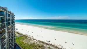 Blick auf den Strand von einem Hochhaus mit blauem Himmel und türkisfarbenem Meer.