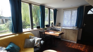 A modern living space with a sofa, dining table, and kitchen area. - In the heart of D-Day" cottage (Barbeville)