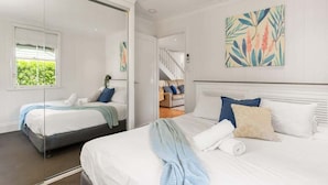 A modern hotel room with two beds, a large mirror, and artwork on the walls. - Family Pool Home | River Fire City Skyline Views (Balmoral)