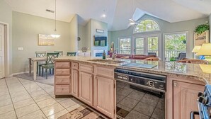 A spacious kitchen with a large island, built-in dishwasher, and a dining area with a table and chairs.