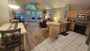 A spacious kitchen with a large island, a dining area with a view, and a living room with a ceiling fan.