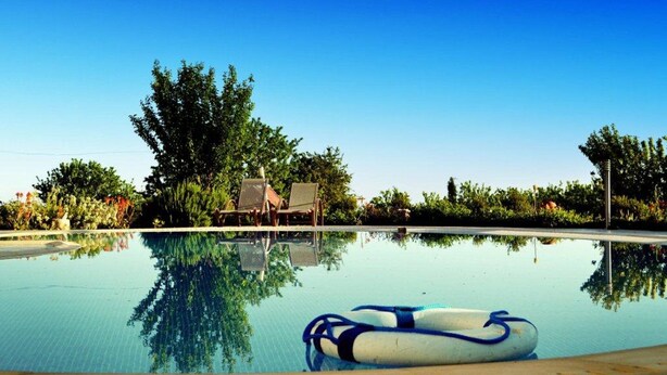 A clear swimming pool with a lifebuoy, surrounded by trees and lounge chairs. - Romantic 5 Bedroom Villa with private salted Pool. Cyprus (Fyti)