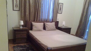 A bedroom with a wooden bed, two bedside tables with lamps, a dark rug, and curtains. - Romantic 5 Bedroom Villa with private salted Pool. Cyprus (Fyti)