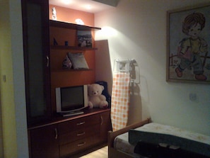 Un dormitorio con un aparador de madera, televisor, cama y un radiador fijado a la pared.
