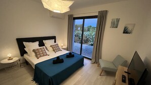 Ein Hotelzimmer mit einem großen Bett, einem Schreibtisch mit einem Laptop, einem Fernseher und Blick ins Freie durch ein Fenster.