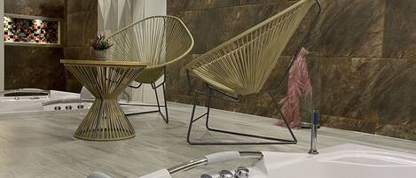 A modern spa area with a large bathtub, two lounge chairs, and a wall-mounted sign reading "hotel truGo SPA".