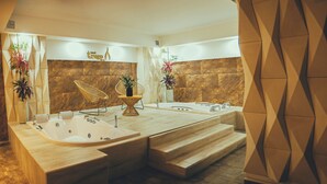 A modern bathroom with a freestanding bathtub, a large mirror, and a seating area with a chair and potted plants. - Trugo Luxury Rooms (Armenia)
