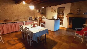 Una cocina rústica con comedor, paredes de piedra y chimenea.