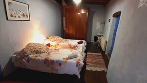 Un pasillo estrecho que conduce a un dormitorio con dos camas, una puerta de madera y una pequeña mesa con una silla.