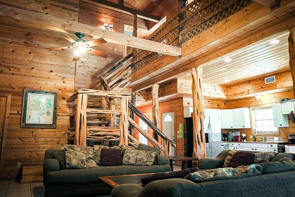 A cozy cabin interior with a wooden staircase, a dining area, and a kitchen. - Leakey River Rental, relax in the peaceful hill country or cool off in the river (Leakey)