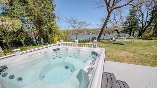 A hot tub with a wooden deck and a view of a lake. - Riverfront Retreat 7mil from MD Renaissance Fest! (Riva)