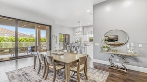 A modern kitchen with a dining area, large windows, and a view of the outdoors. - Live in Luxury; Walk to the beach, shops and more (Marco Island)