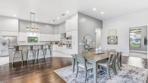 A modern kitchen with stainless steel appliances, a bar area, and a dining space with a large table and chairs.