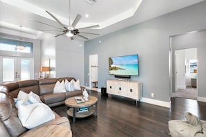 A modern living room with a leather sofa, a coffee table, and a flat-screen TV mounted on the wall.