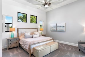 A bedroom with a bed, nightstands, a bench, and artwork on the walls.
