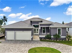 A modern two-story house with a grey roof, two garage doors, and a well-maintained lawn.