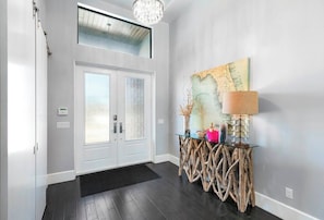 A modern entryway with a glass door, a wooden console table, and a map artwork on the wall. - Live in Luxury; Walk to the beach, shops and more (Marco Island)