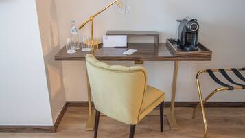 Un espacio de trabajo moderno con escritorio, silla, lámpara, máquina de café y una botella de agua.
