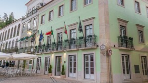Un edifici amb diverses finestres, un balcó amb barana i banderes.