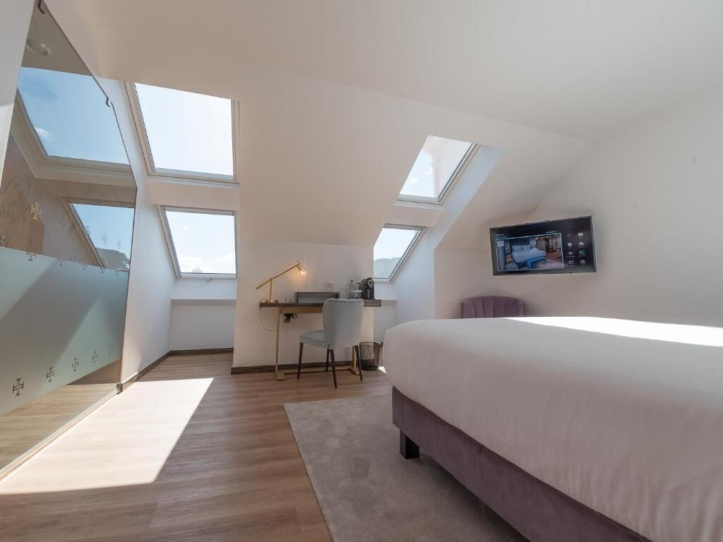 A bedroom with a large bed, skylights, a desk, and a chair.