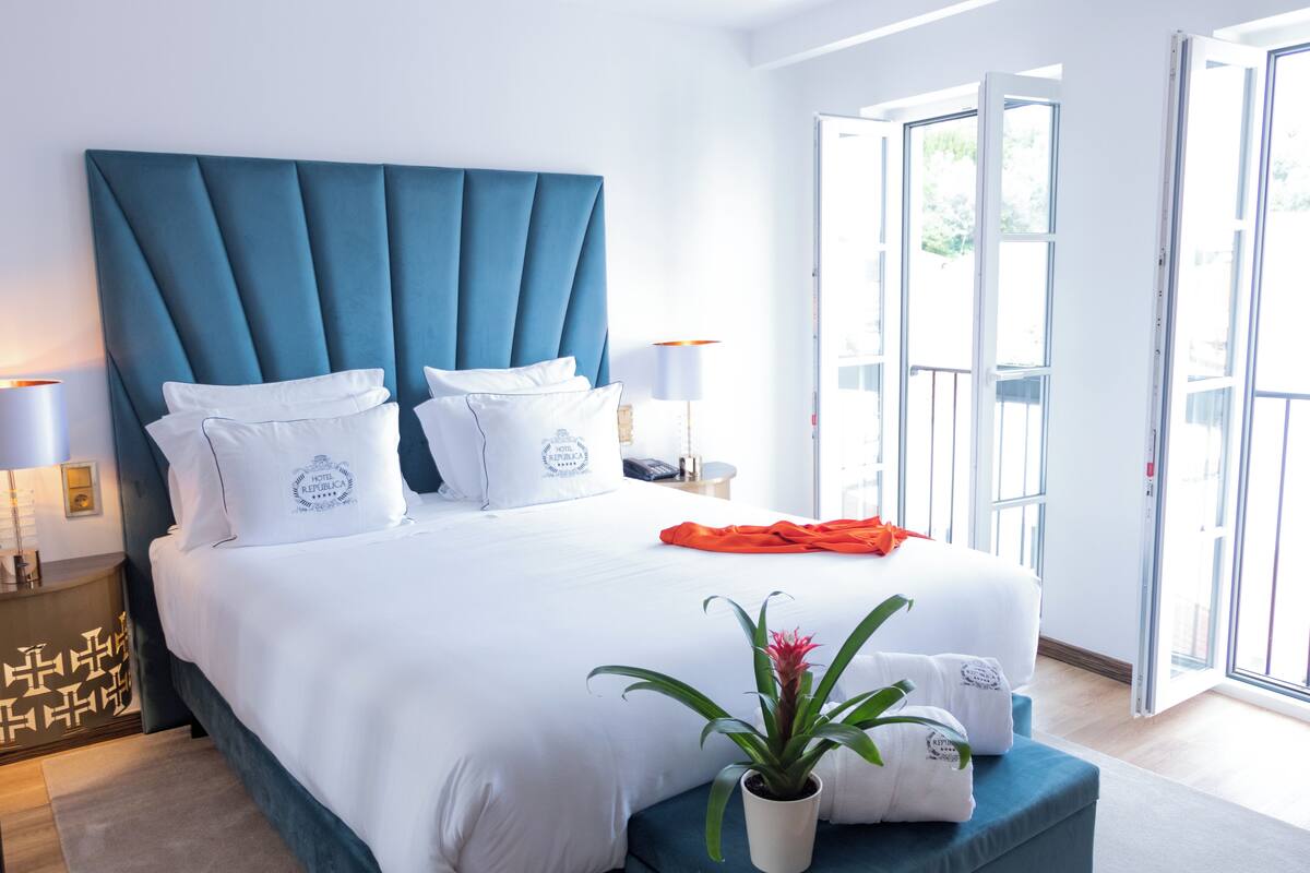 Une chambre d’hôtel moderne avec un grand lit, une plante en pot et un balcon doté de portes vitrées.