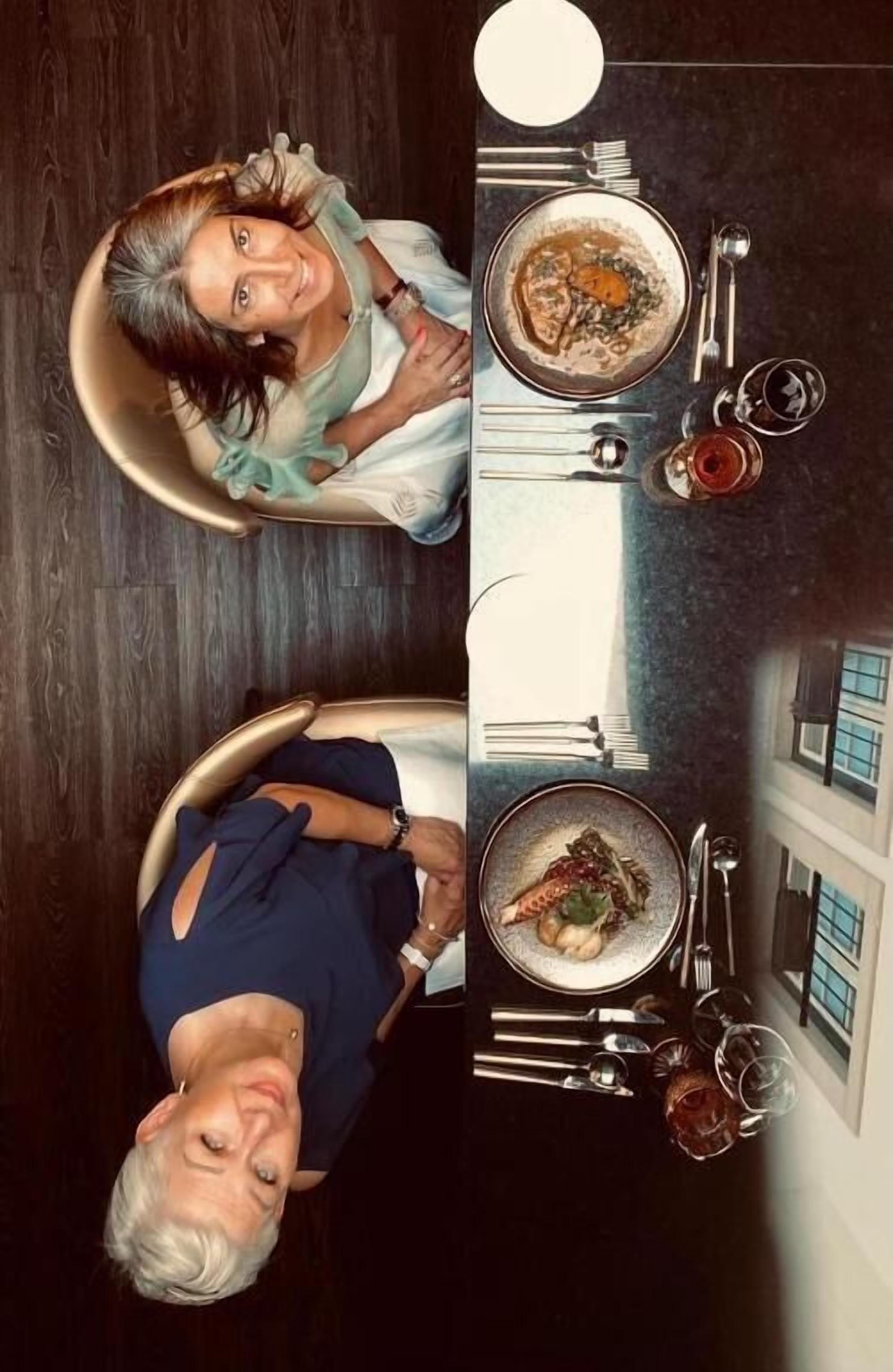 Een eetruimte met twee tafels voor twee personen, elk met een kom soep en bestek.