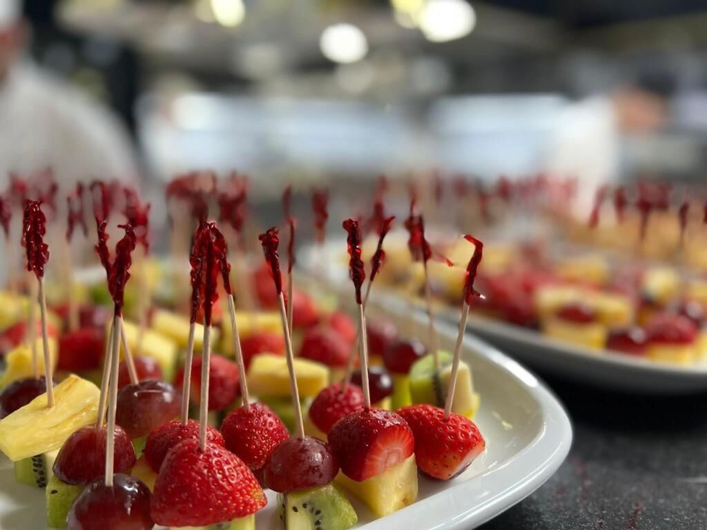 Un plato de brochetas de frutas con fresas y kiwi.