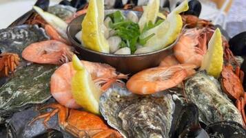 Un plateau de fruits de mer comprenant divers crustacés et crevettes, agrémenté de tranches de citron et d’herbes aromatiques, présenté sur une table.