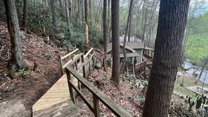 Eine Holztreppe führt zu einer Hütte in bewaldetem Gebiet.