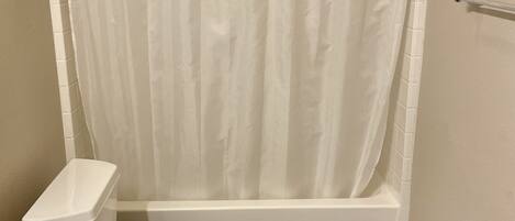 Bañera con ducha, toallas, jabón, papel higiénico