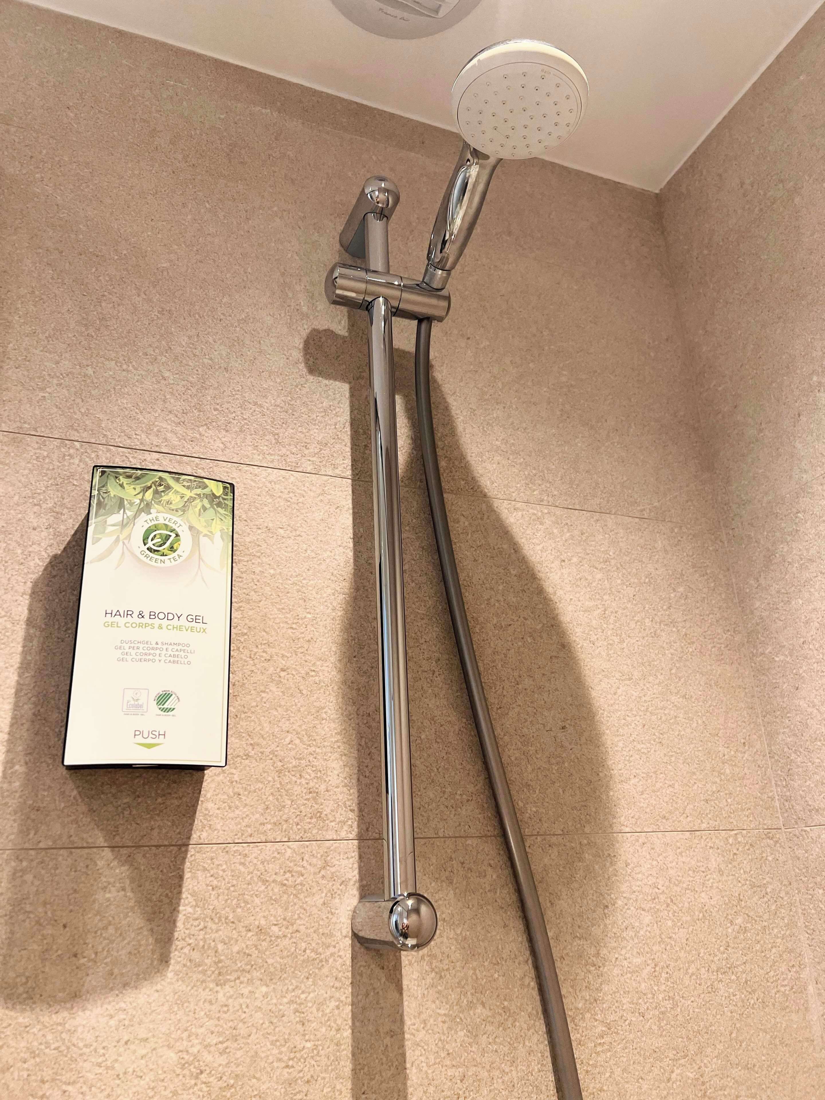 A shower with a handheld attachment and a boxed hair and body gel product.