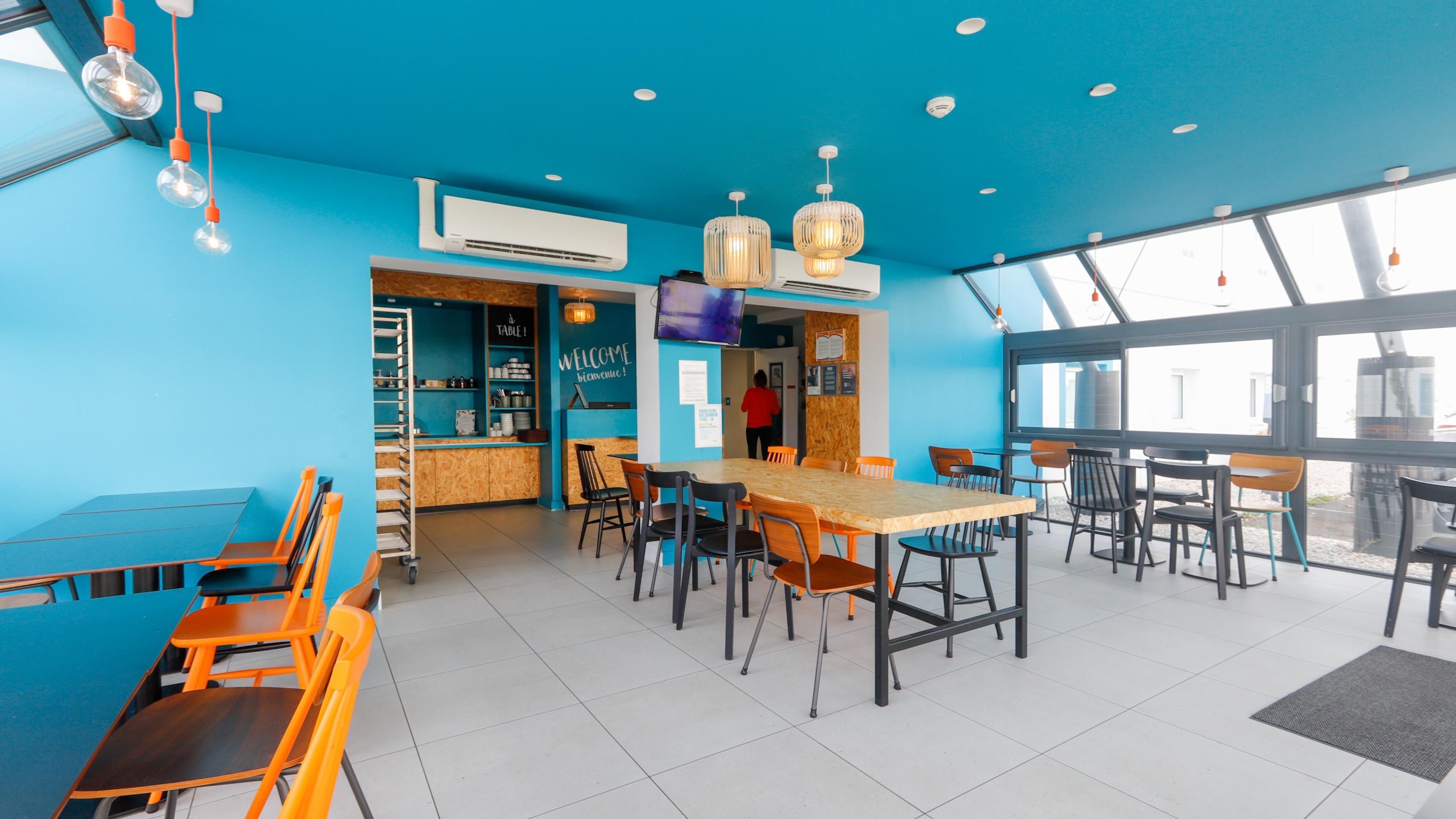 A restaurant interior with blue walls, wooden tables, and chairs.