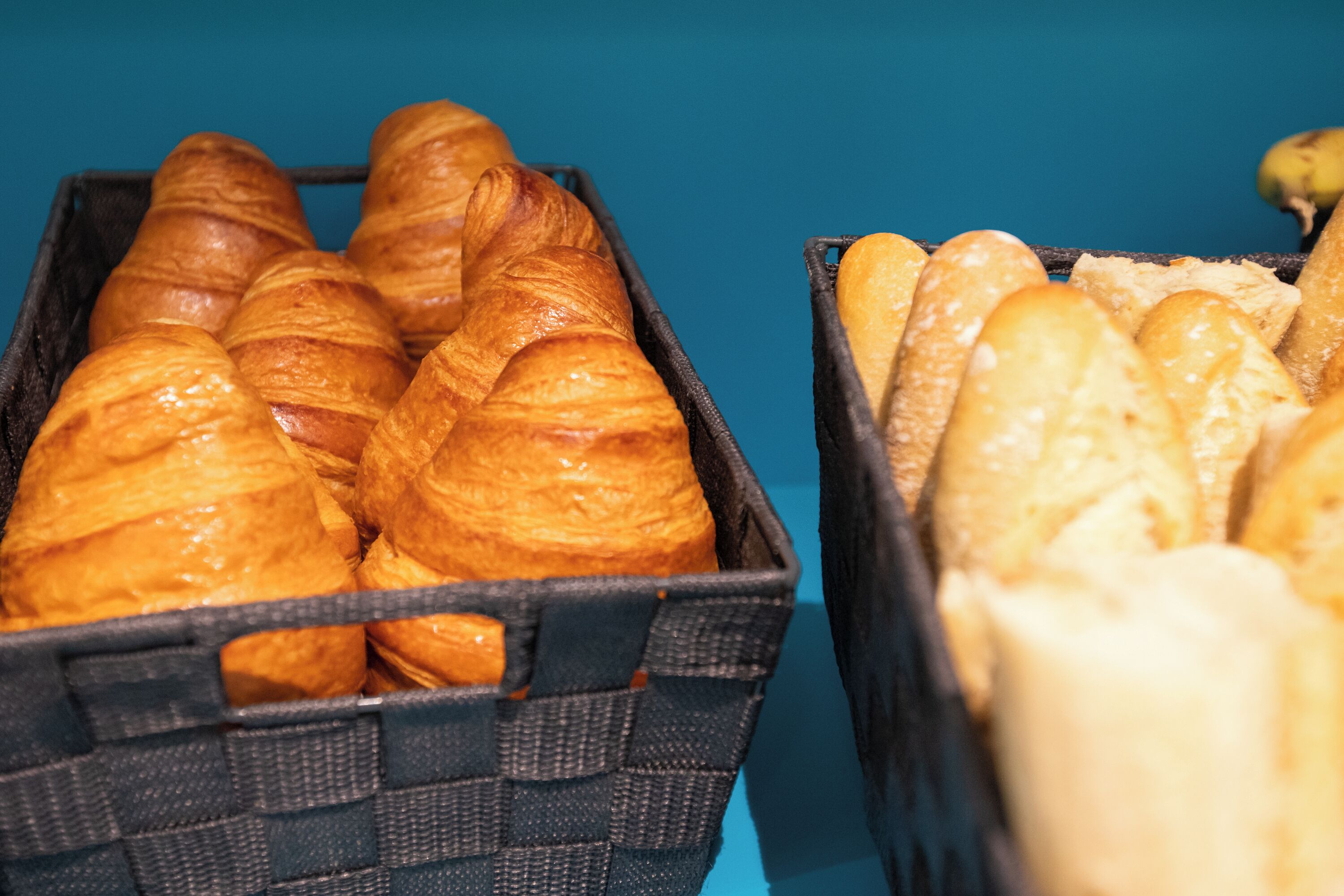 Two baskets of bread, one with croissants and the other with baguettes.