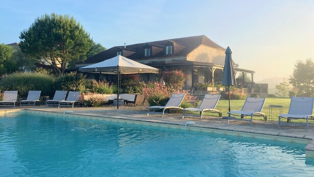 A pool area with lounge chairs and a covered seating area.