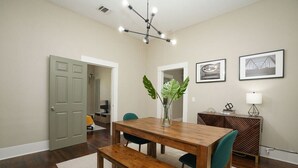 Un coin repas avec une table en bois, deux chaises, un banc, un vase avec une plante et des tableaux encadrés accrochés au mur.