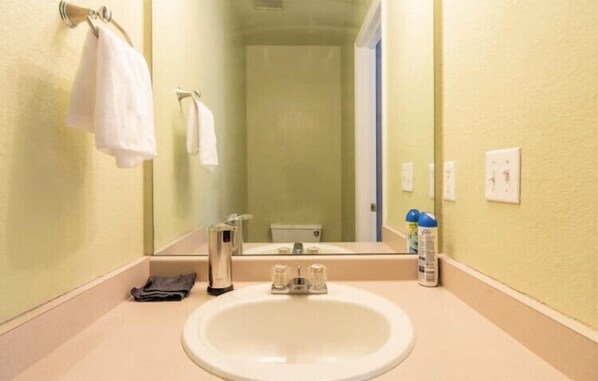 Un baño con lavamanos, espejo y toallero.