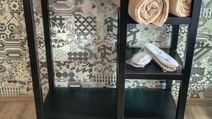 Una mesita auxiliar de metal negro sobre un fondo de papel tapiz con un diseño.