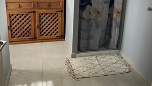 Une salle de bain avec un meuble-lavabo en bois, un rideau de douche et un carrelage au sol.