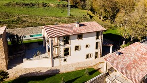 A two-story building with a tiled roof, a swimming pool, and a stone wall. - DALT'S COUNTRY (Sant Joan de les Abadesses)