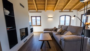 A modern living room with a wooden ceiling, built-in entertainment unit, and a large sectional sofa. - DALT'S COUNTRY (Sant Joan de les Abadesses)
