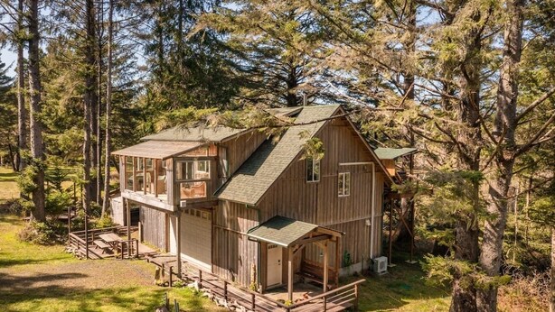 Eine zweistöckige Holzhütte mit einer Terrasse, umgeben von Bäumen.