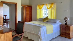 A bedroom with a bed, bedside table, lamp, chair, and wardrobe.