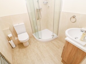Un baño con inodoro, ducha con cerramiento de vidrio y lavamanos.
