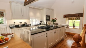 A spacious kitchen with white cabinets, a central island, and a wooden floor. - The Barn (Bishop Auckland)