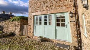 A stone building with a light blue door and a sign reading "The Barn". - The Barn (Bishop Auckland)