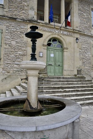 A stone building with a green door and steps leading up to it. Flags are visible on the building.